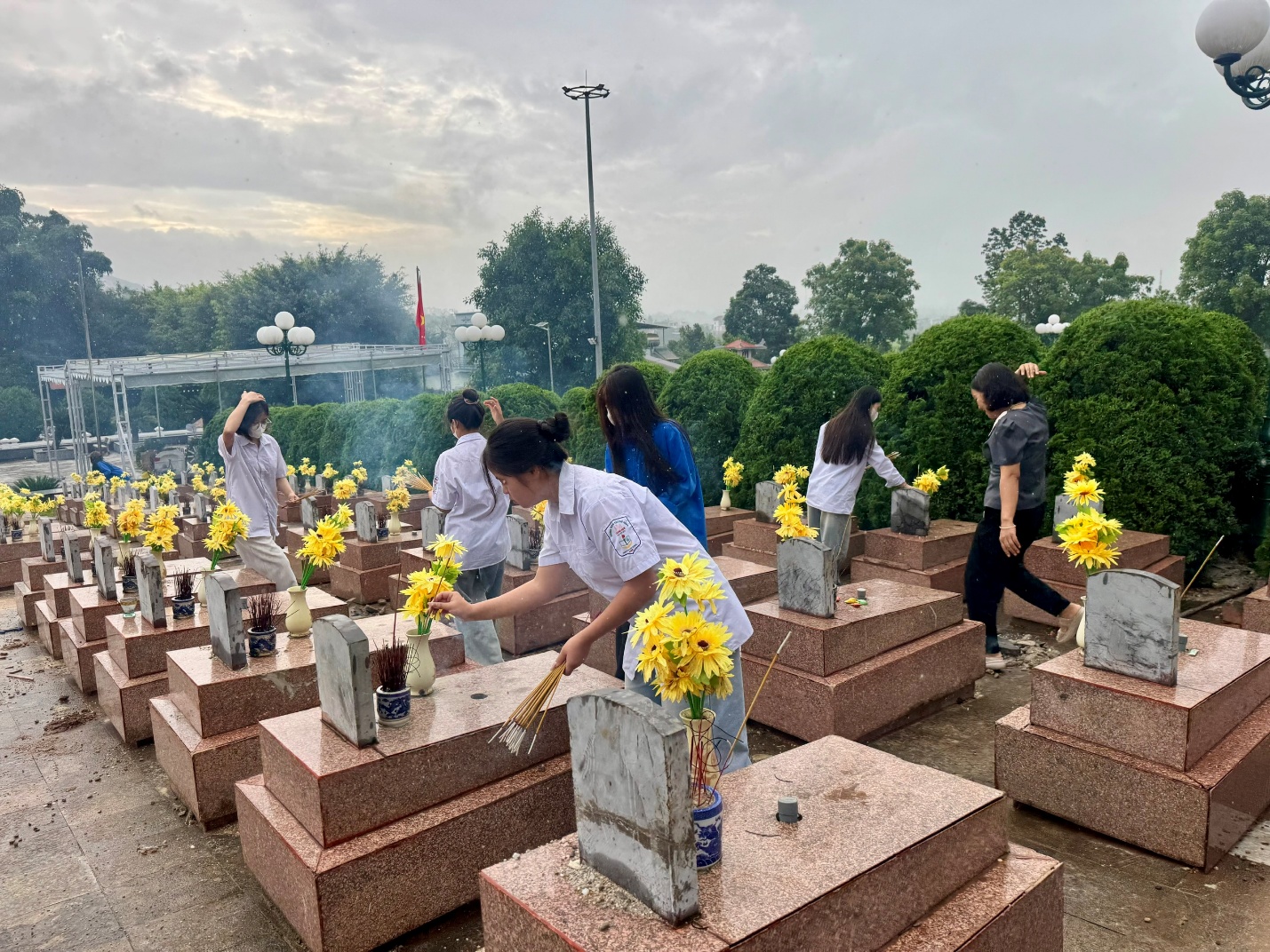 'A group of people standing in a cemetery
Description automatically generated'